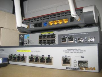 A router stacked on an HP ProCurve 2520-8-PoE and another small ProCurve PoE switch